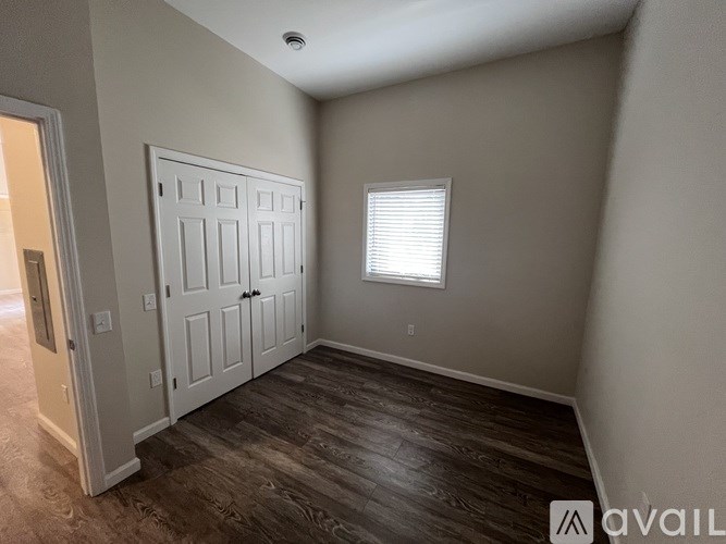 A room with a white door and a window with blinds.