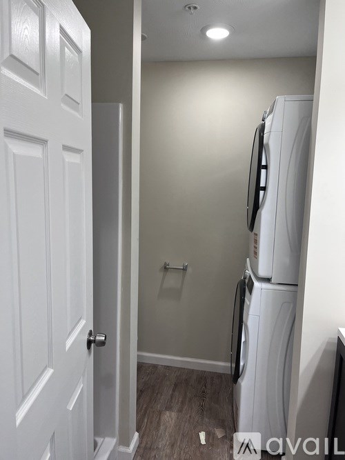 A white door is open to a small kitchen with a white refrigerator.