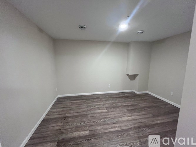 A room with wooden flooring and white walls is available for rent or sale.