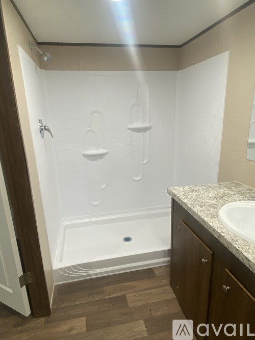 A bathroom with a white shower and wooden floors.