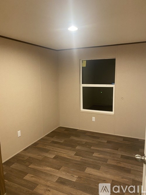 A room with a window and wooden flooring.