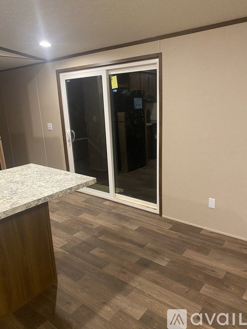 A room with a marble counter and wooden flooring with a glass door.