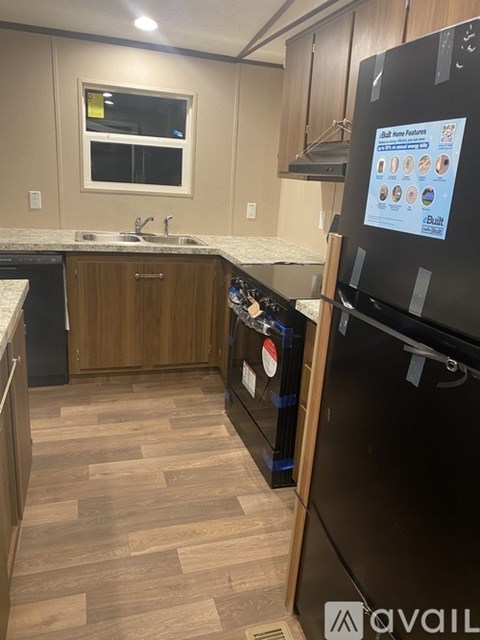 A kitchen with a black fridge and wooden floors.