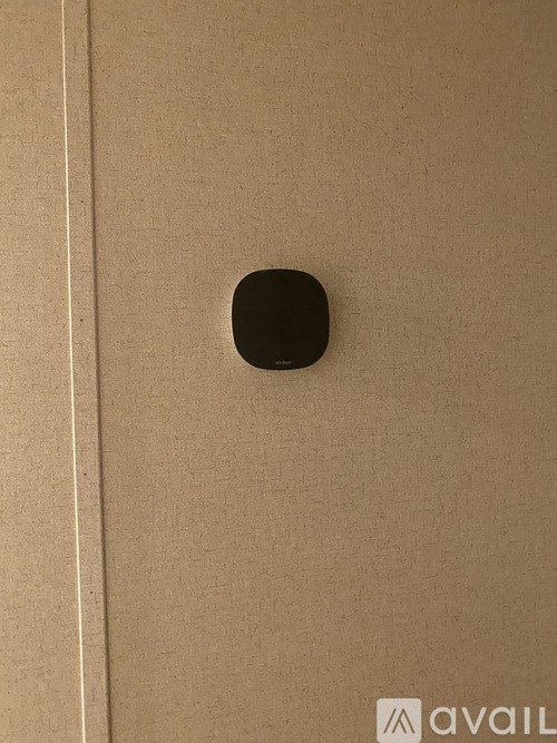 A black square object is mounted on a beige wall.
