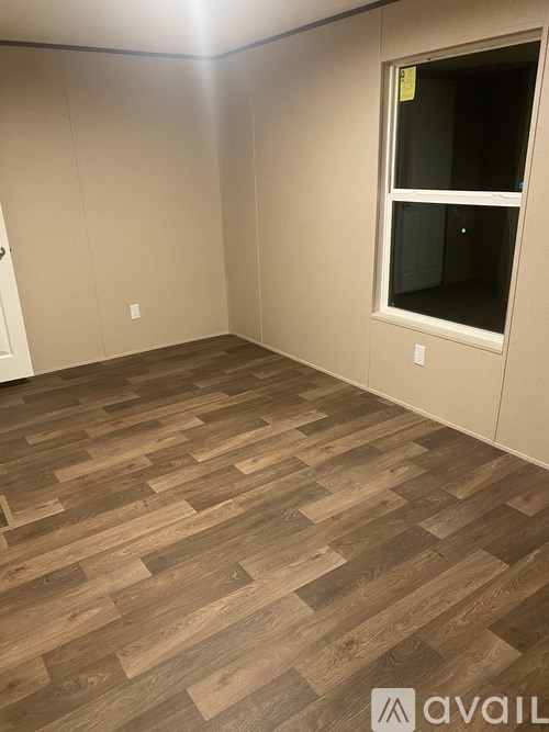 A room with wooden flooring and a window.