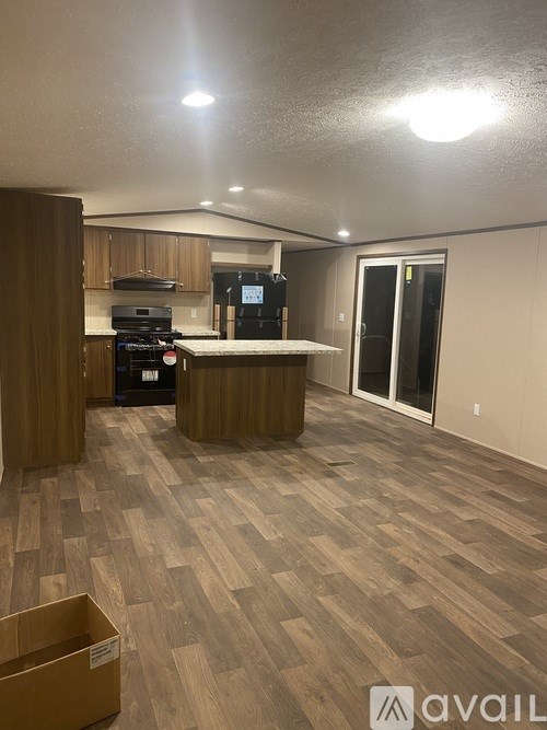 A kitchen area with wooden flooring and a box on the floor.