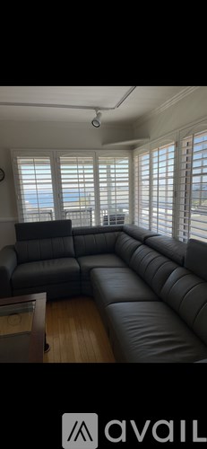 A living room with a grey leather sofa and a ceiling fan.