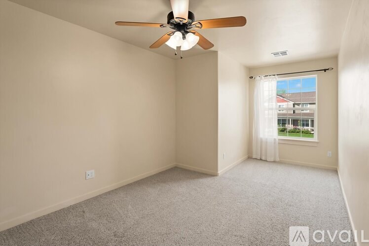 A room with a ceiling fan and carpeted floor.