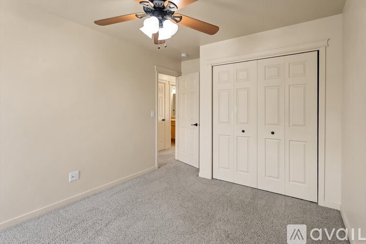 A room with a ceiling fan and a door.
