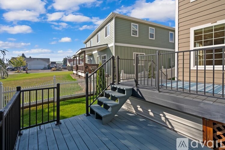 A house with a deck and a balcony overlooking a grassy area.