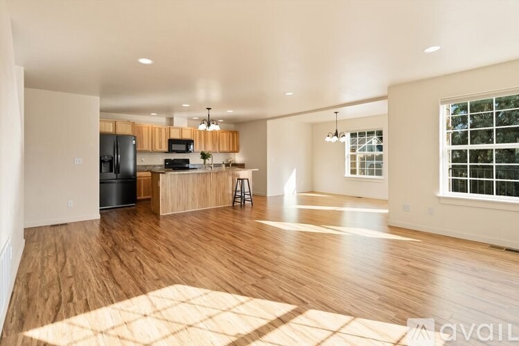 A spacious kitchen and living room with wooden floors and white walls.