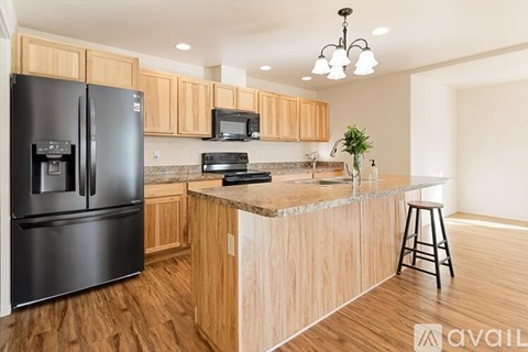 A kitchen with wooden cabinets and a black refrigerator.