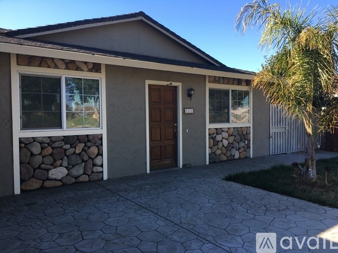 A house with a stone wall and a brown door is for sale.