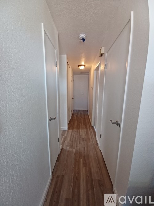 A long hallway with white walls and wood flooring.