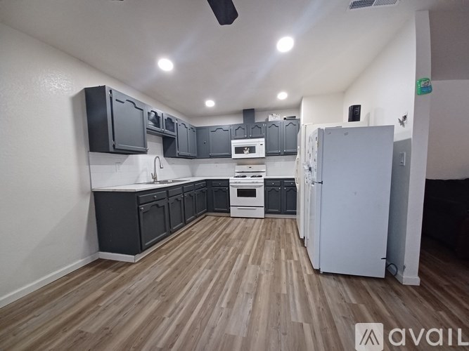A kitchen with wooden floors and a white refrigerator.