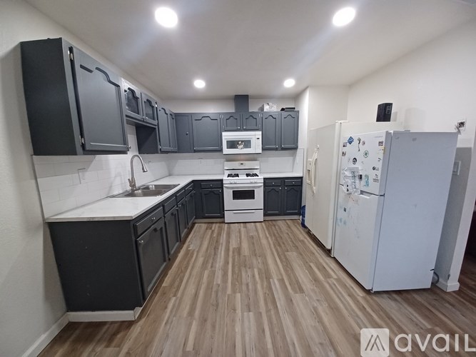 A kitchen with black cabinets and a white fridge.