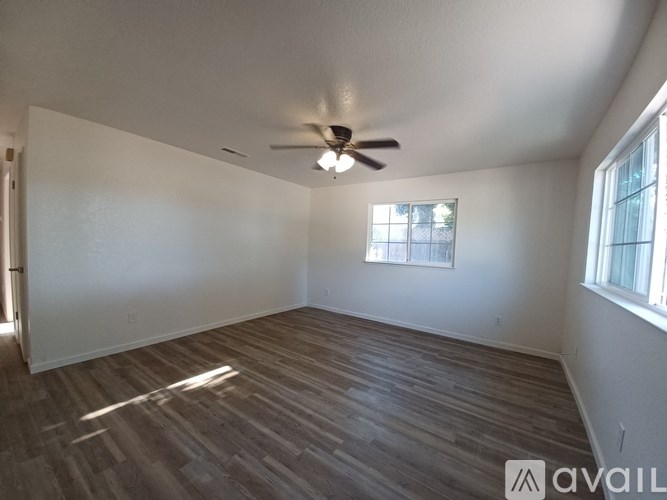 A room with a ceiling fan and wooden flooring.