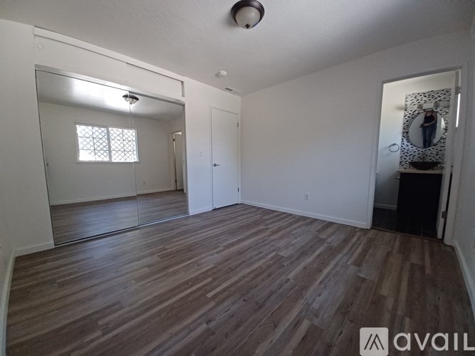 A room with wooden flooring and a mirror on the wall.