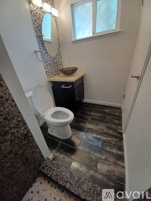 A bathroom with a toilet, sink, and mirror.