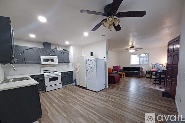 A kitchen with a refrigerator, sink, and stove.