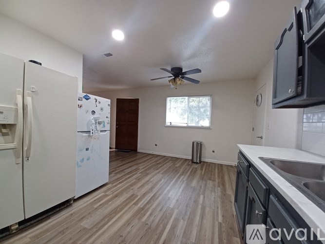 A kitchen with a white fridge and wooden floors.