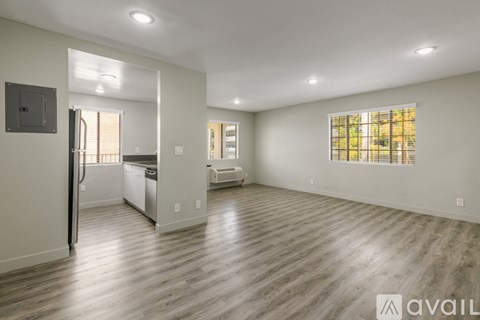 A spacious living room with a kitchen area in the background.