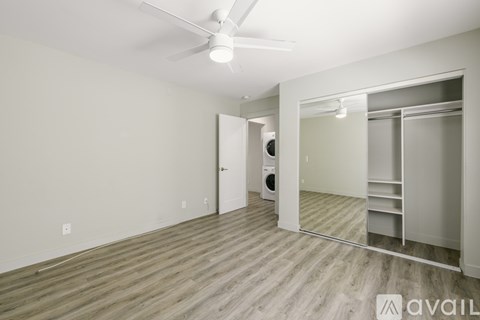 A room with a fan and a door leading to a bathroom.