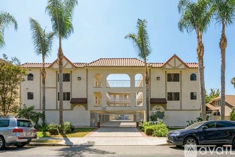 A large house with a red tile roof and palm trees in front.