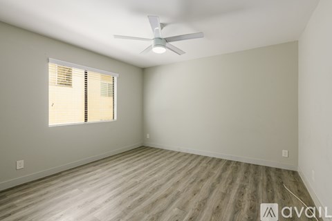 A room with a ceiling fan and a window with blinds.