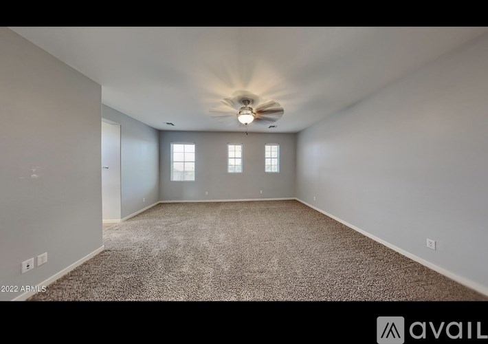 A spacious room with a carpeted floor and a ceiling fan.