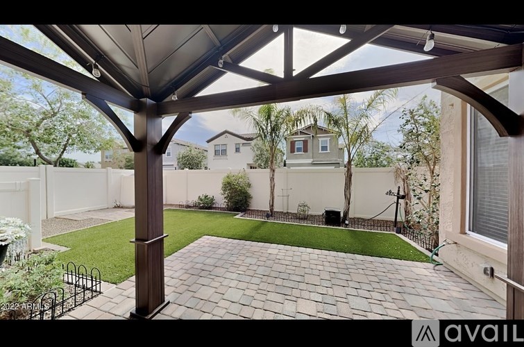 A patio with a black metal fence and a brick walkway.
