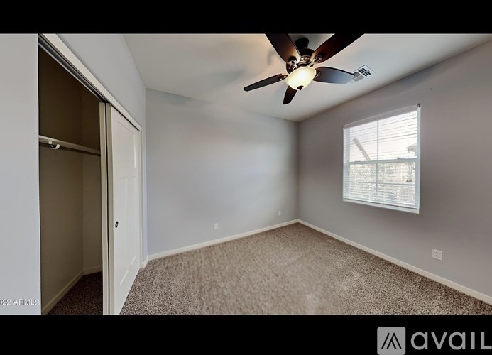 A room with a ceiling fan and a window with blinds.