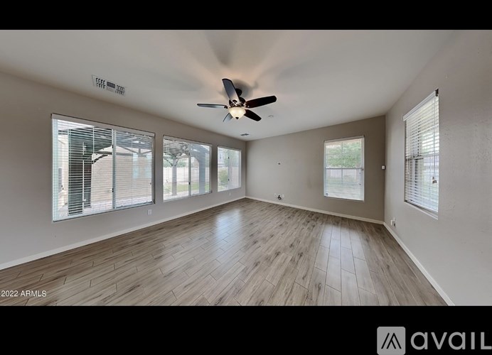 A spacious room with a ceiling fan and large windows.