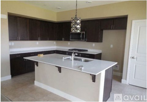 A kitchen with a white countertop and dark brown cabinets.