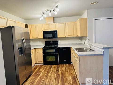 A kitchen with wooden cabinets and black appliances.