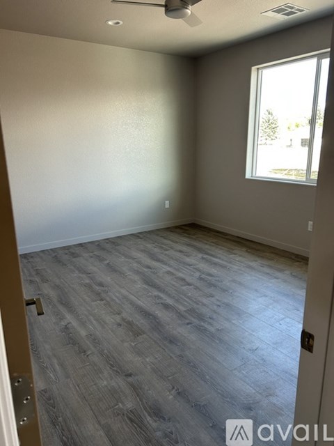 A room with a window and a wooden floor.