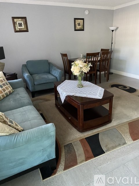 A living room with a blue couch, a wooden coffee table, and a dining table with chairs.