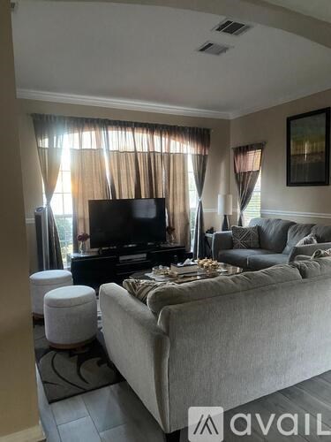 A living room with a grey couch, a television, and a painting on the wall.