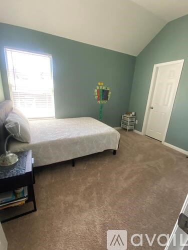 A bedroom with a bed, nightstand, and window.