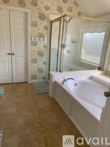 A bathroom with a bathtub, a mirror, and a door.
