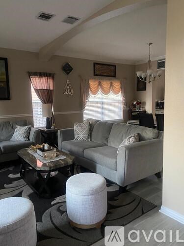 A living room with a grey couch, a coffee table, and a chandelier.