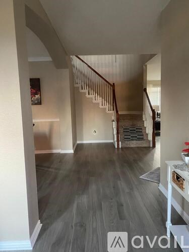 A hallway with a staircase and a white railing.