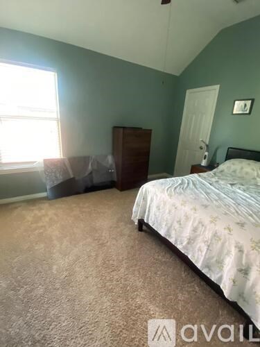 A bedroom with a bed, dresser, and window.