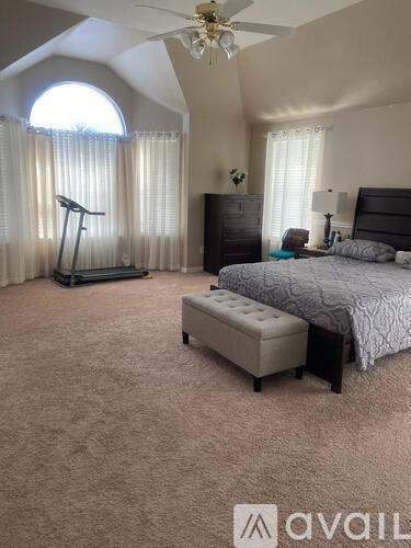 A bedroom with a bed, dresser, and exercise equipment.