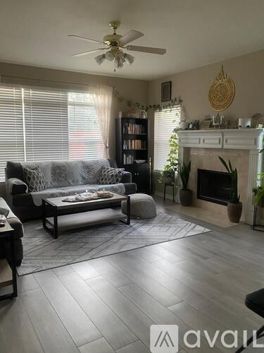 A living room with a fireplace, a couch, a chair, a coffee table, and a bookshelf.