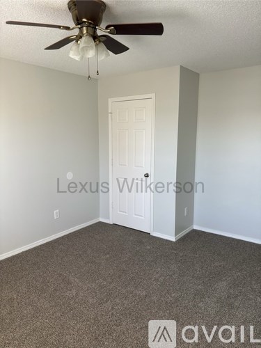 A room with a ceiling fan and a door.
