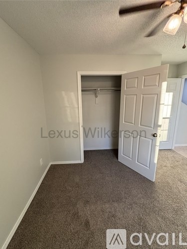 A room with a carpeted floor and a ceiling fan.