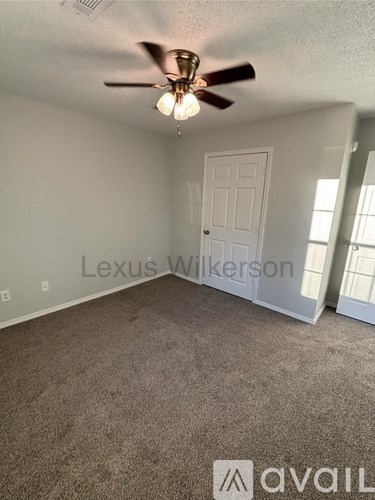 A room with a ceiling fan and a door.