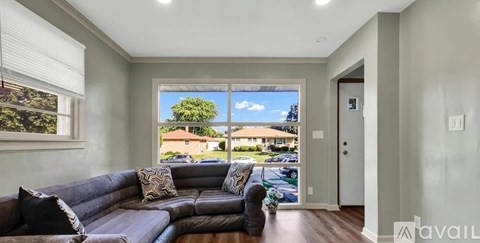 A living room with a couch and a window overlooking a residential area.