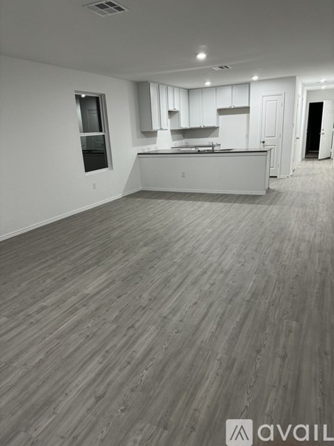 A spacious kitchen with white cabinets and a wooden floor.